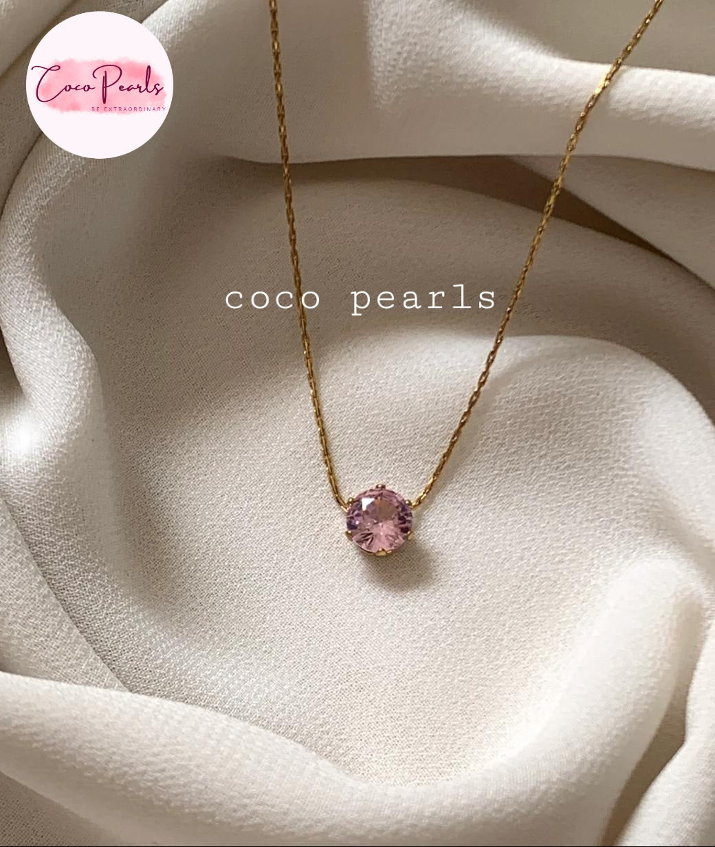 Coco pearls stainless Steel anti tarnish delicate gold chain necklace with a single round pink gemstone pendant, displayed on draped cream-colored fabric.
