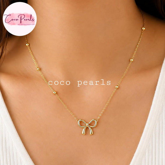 Coco pearls stainless Steel anti tarnish gold necklace with a small bow pendant and small bead accents, shown worn on a model's neck.