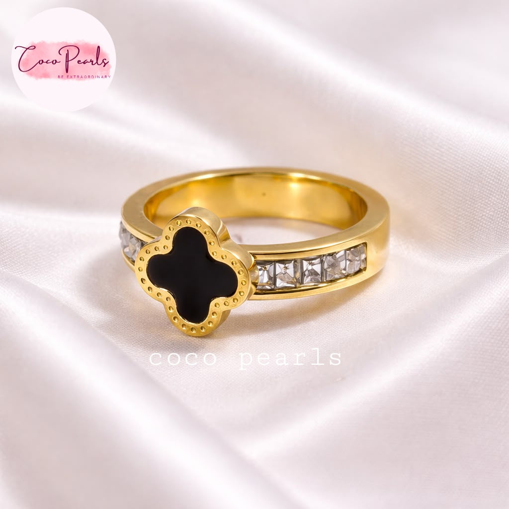 Coco pearls stainless Steel anti tarnish gold diamond studded adjustable ring with black clover in center displayed on simple background