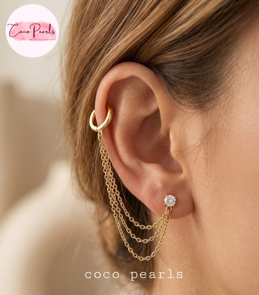 Coco pearls stainless Steel anti tarnish close-up of a model's ear showcasing a gold ear cuff with three dangling chain drops and a small gold stud earring with a clear gemstone.