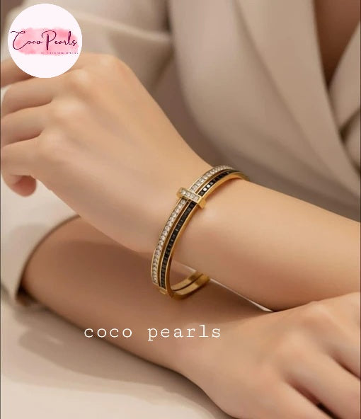 Coco pearls stainless Steel anti tarnish gold bangle bracelet with black and white stones accents, worn on a model's wrist.