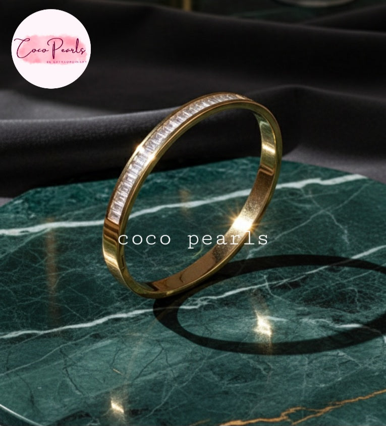 Coco Pearls Stainless Steel Anti Tarnish Gold diamond line handcuff with diamonds on a green marble surface