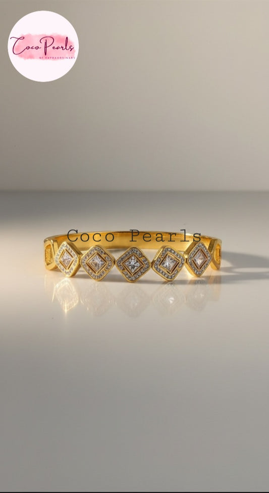Coco Pearls Stainless Steel Anti Tarnish Gold diamond accent handcuff bangle bracelet with diamond studded square clear stones on a gray background