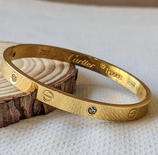 Coco Pearls Stainless Steel Anti Tarnish Gold diamond studded handcuff bangle Cartier bracelet on a textured surface