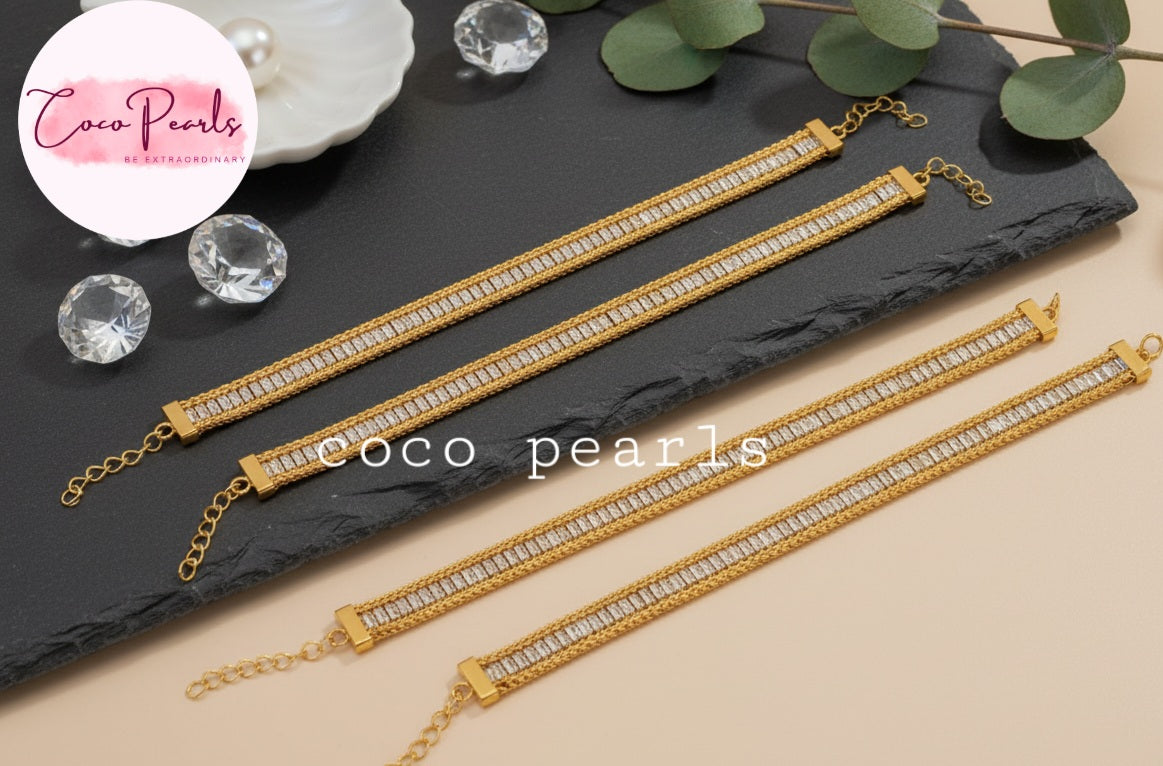 Coco Pearls Stainless Steel Anti Tarnish Gold elegant twist bracelet Gold bracelets with clear stones on a dark slate surface