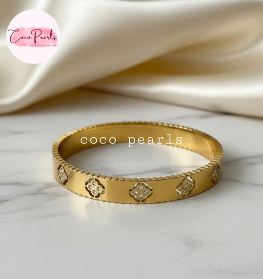 Coco Pearls Stainless Steel Anti tarnish Gold eternal bloom handcuff with floral designs on a marble surface