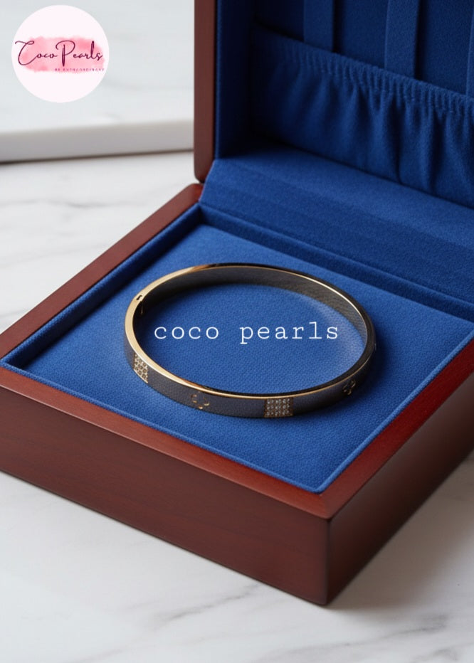 Coco Pearls Stainless Steel Anti tarnish Gold Gleam Hinged Handcuff Bangle bracelet in a blue jewelry box