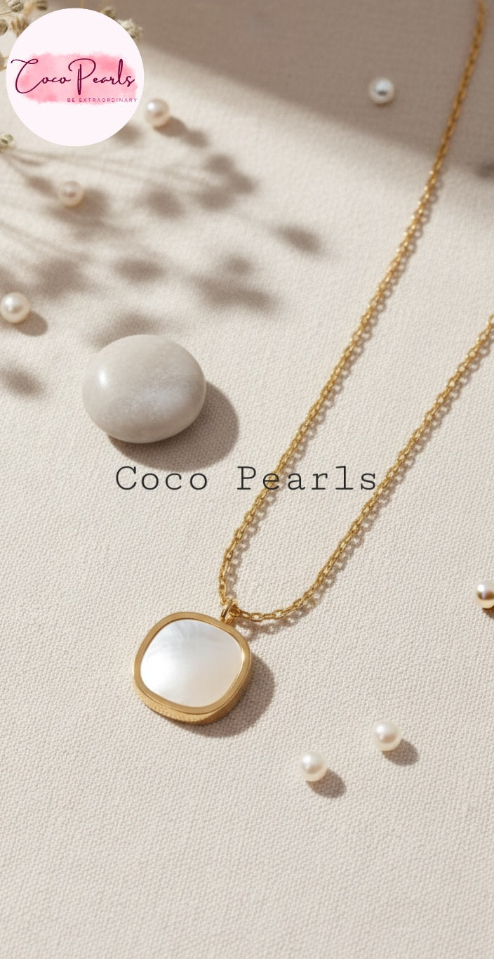 Coco Pearls Stainless Steel Anti Tarnish luminous drop Gold necklace with a white pendant on a beige surface