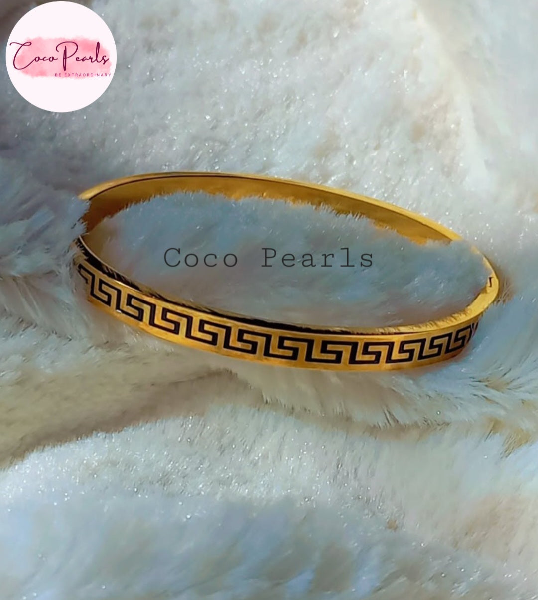 Coco Pearls Stainless Steel Anti Tarnish Gold pattern charm handcuff bangle bracelet with black pattern on a white fluffy background