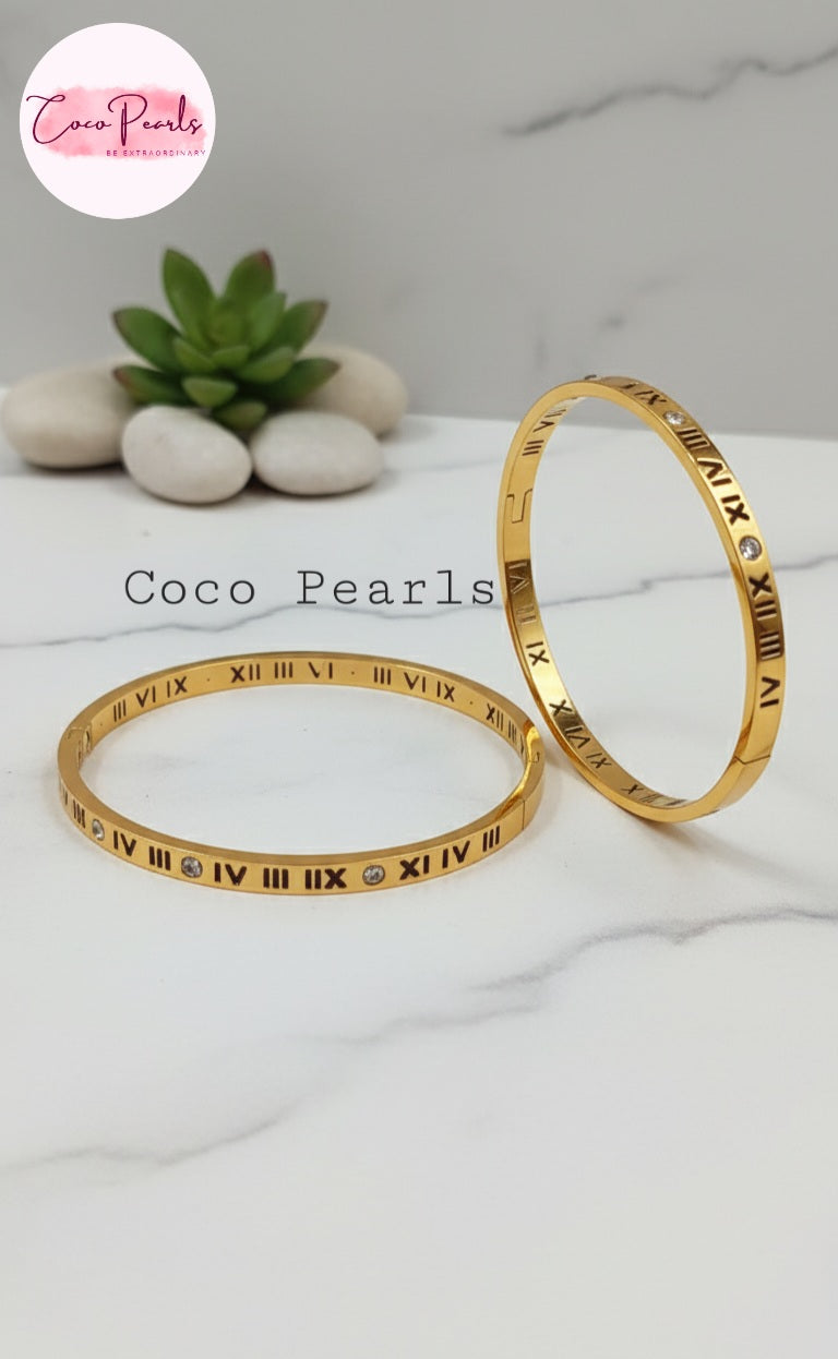 Coco Pearls Stainless Steel Anti Tarnish Two gold roman handcuff bracelets with Roman numeral design on a white surface