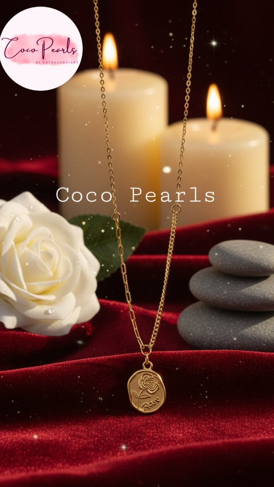 Coco Pearls Stainless Steel Anti Tarnish Gold rose charm necklace with a pendant with roe engraved displayed on a red surface with candles and a white rose