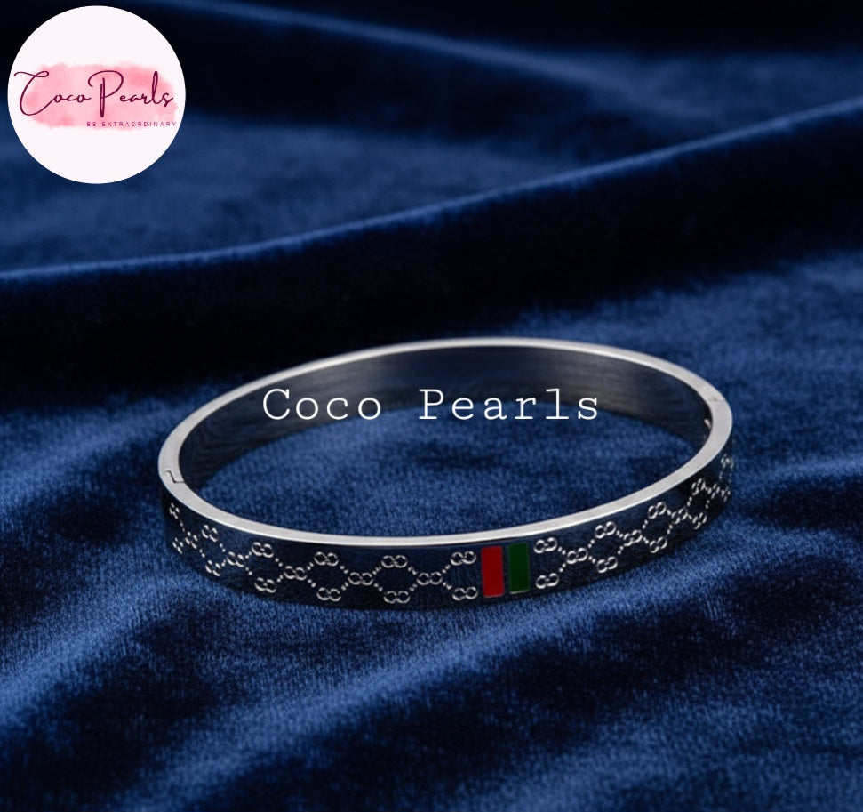 Coco Pearls Stainless Steel Anti Tarnish Silver vibe handcuff bracelet with red and green accents on a blue fabric background