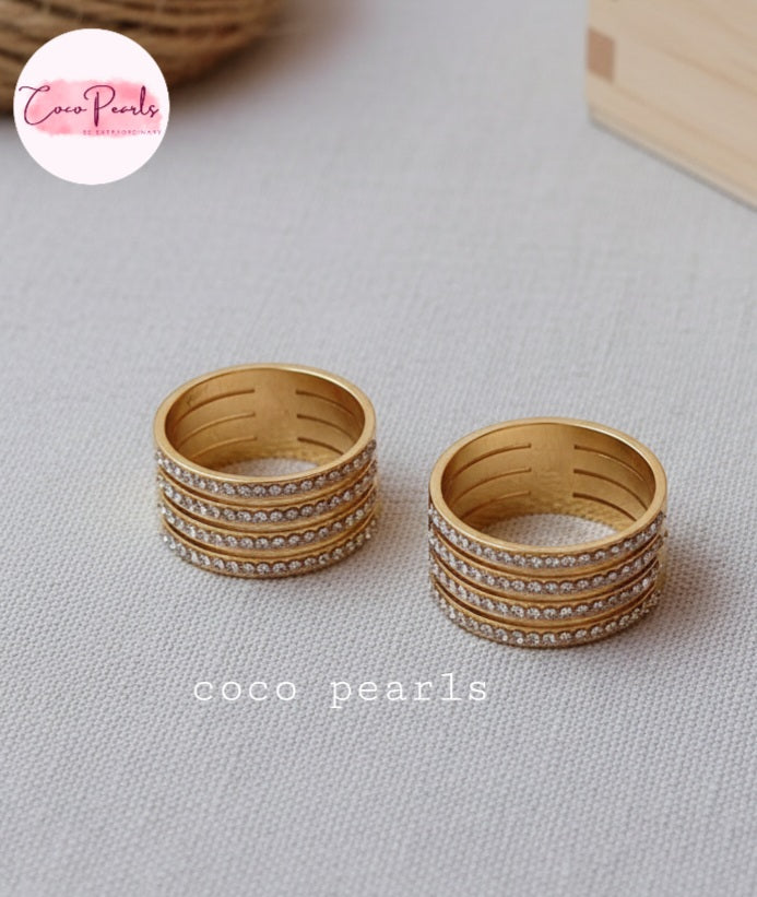 Coco Pearl stainless steel Anti tarnish Gold stellar stack ring with rhinestones Set of gold rings on a light gray surface