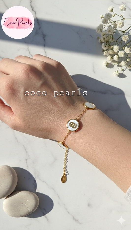 Coco Pearls Stainless steel anti tarnish Hand wearing a white disc gold bracelet with a charm on a light background