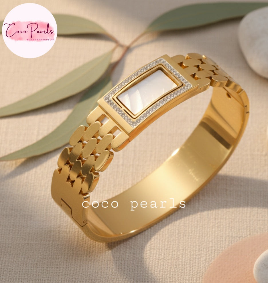 coco pearls stainless steel Golden aura handcuff bracelet with a white center on a beige background