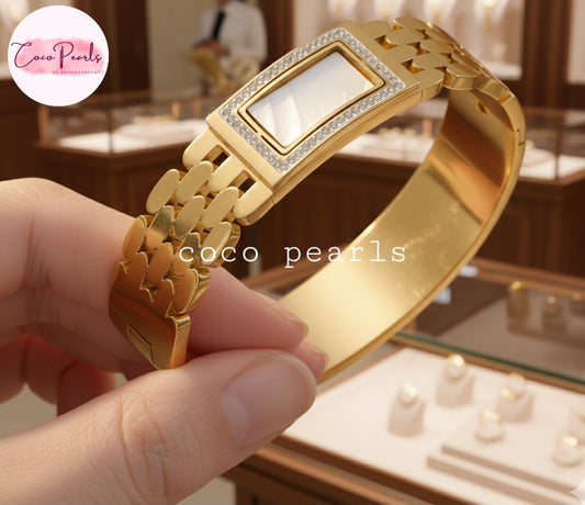 coco peals stainless steel Golden aura bracelet handcuff with diamond accents held by a hand