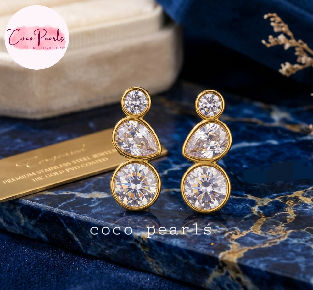 coco pearls stainless steel anti tarnish tri sparkle studs Gold and crystal earrings on a blue surface