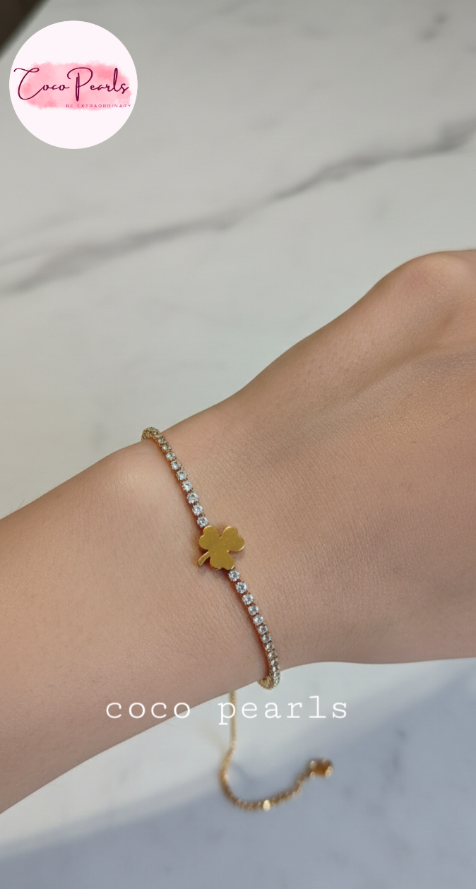 coco pearls stainless steel anti tarnish lucky charm bracelet. diamond studded with golden clover in center displayed on hand