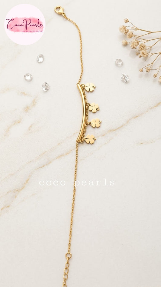 Coco pearls stainless Steel anti tarnish gold-toned chain bracelet with a curved bar and three small clover charms, displayed on a light marble surface 