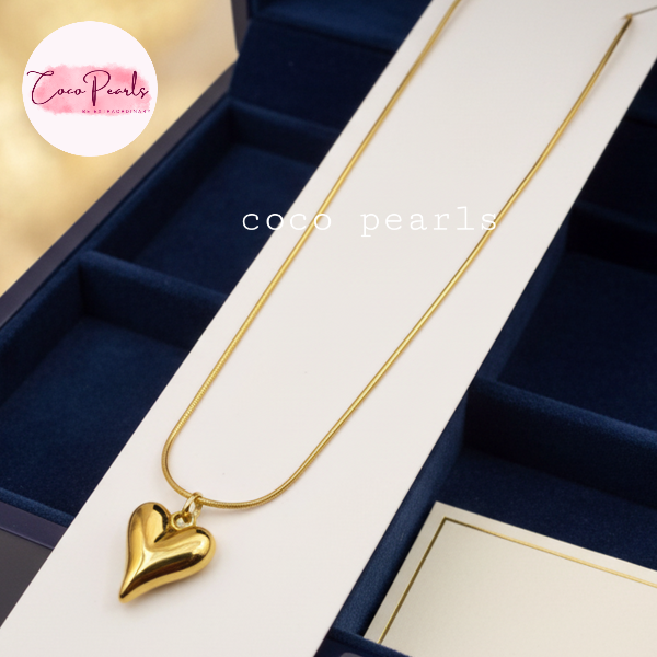Coco pearls stainless Steel anti tarnish gold heart pendant displayed on simple background 