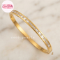 Coco pearls stainless Steel anti tarnish gold bangle bracelet featuring a channel-set row of clear baguette and rectangle-cut stones, displayed on a light marble surface.