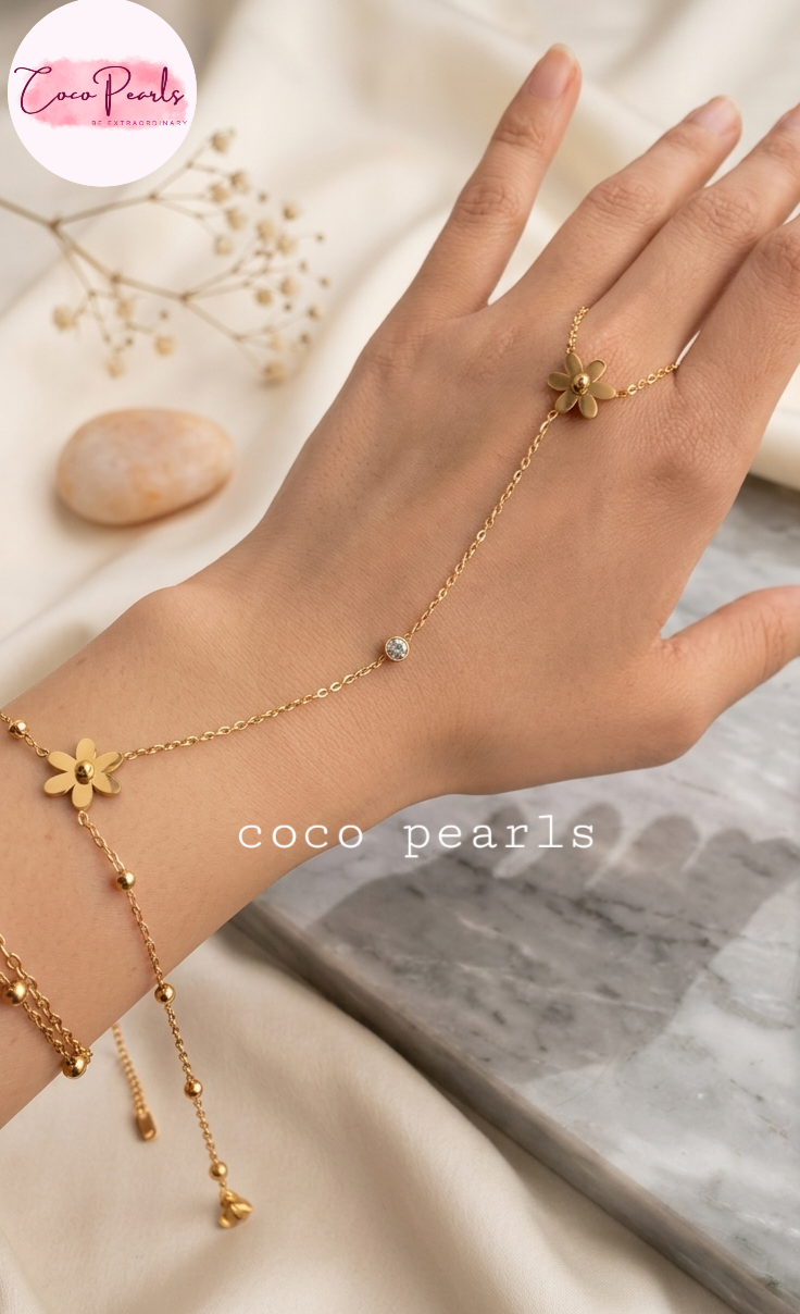 Coco pearls stainless Steel anti tarnish delicate gold chain hand chain bracelet with flower charms and a small bead, shown worn on a person's wrist and ring finger.