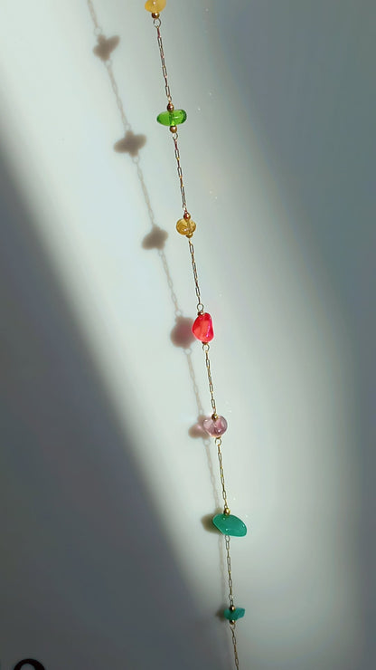 Coco pearls stainless Steel anti tarnish  delicate gold chain adorned with small faceted gemstone beads in yellow, green, red, pink, and teal, set against a white wall with soft shadows.