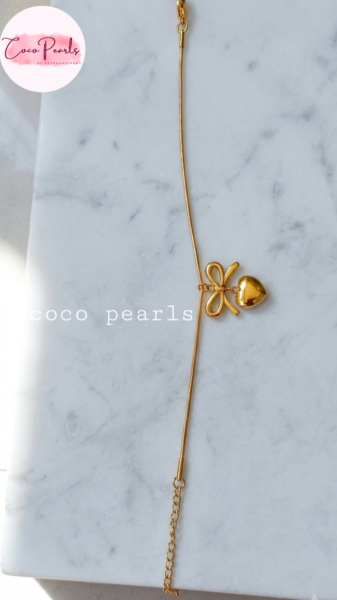 Stainless Steel Anti Tarnish bracelet with a bow-shaped clasp displayed a marble surface, branded 'Coco Pearls'.