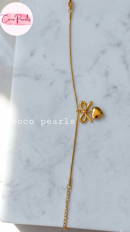 Stainless Steel Anti Tarnish bracelet with a bow-shaped clasp displayed a marble surface, branded 'Coco Pearls'.
