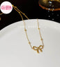 Coco pearls stainless Steel anti tarnish gold necklace with a bow-shaped pendant and small bead accents, displayed on a white plate.