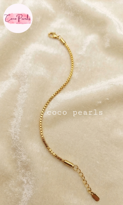 Coco pearls stainless Steel anti tarnish gold chain bracelet with a lobster clasp and extension chain, displayed on a soft beige fabric background.
