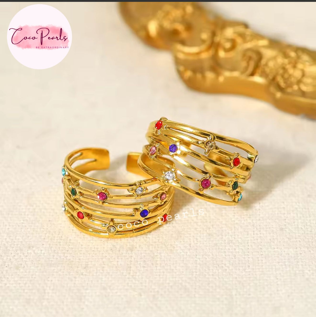 Coco pearls stainless Steel anti tarnish Gold multi-band ring with colorful gemstone accents, displayed on a textured cream fabric background 