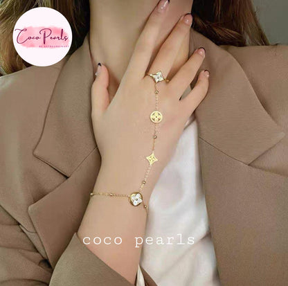 Stainless Steel Close-up of a hand wearing a gold bracelet with star-shaped charms, against a neutral background. Coco Pearls logo is visible.