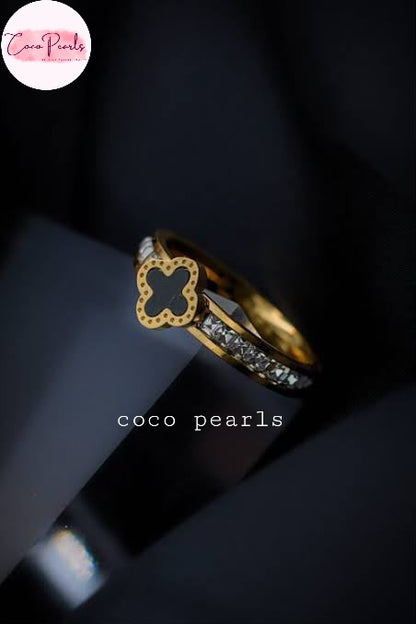 Coco pearls stainless Steel anti tarnish gold diamond studded ring with black clover in center displayed on simple background 