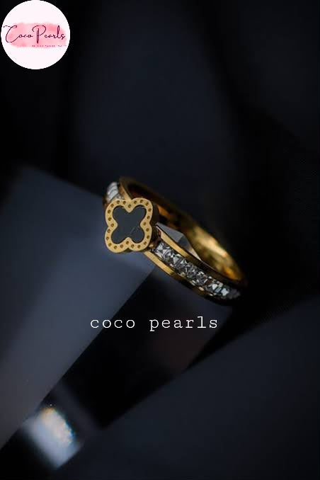 Coco pearls stainless Steel anti tarnish gold diamond studded ring with black clover in center displayed on simple background 