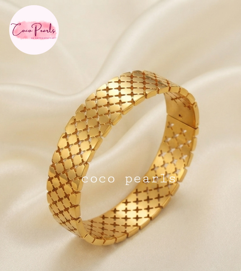 Coco pearls stainless Steel anti tarnish gold-plated metal link bracelet with a woven, lattice-like pattern, displayed on a draped cream satin fabric.