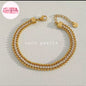 Coco pearls stainless Steel anti tarnish gold-plated tennis-style bracelet with rows of clear rhinestones, shown on a light textured background.