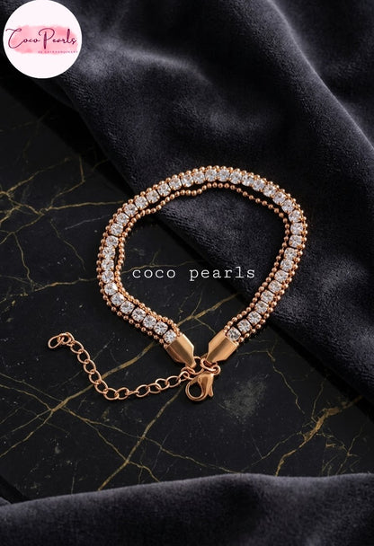 Coco pearls stainless Steel anti tarnish gold beaded bracelet with clear crystal-encrusted links, displayed on a black velvet fabric background with a gold marble texture.