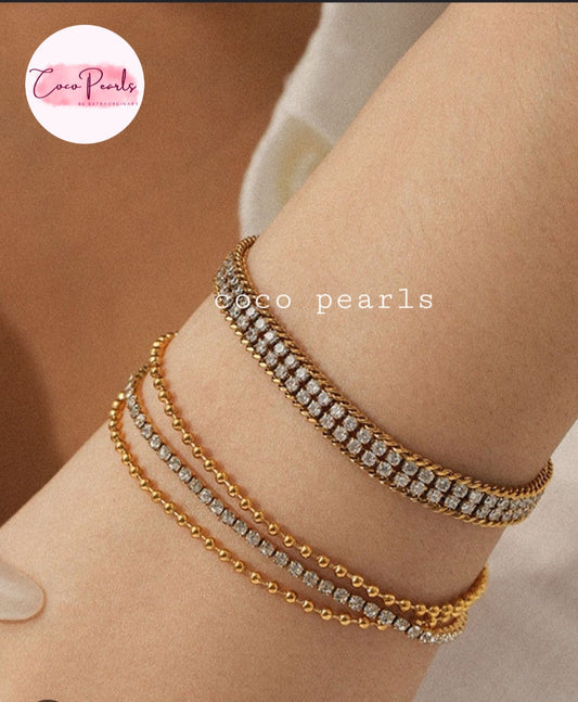 Coco pearls stainless Steel anti tarnish Three delicate gold bracelets with clear pavé and bead details, stacked on a person's wrist.