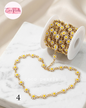 Coco pearls stainless Steel anti tarnish Gold chain embellished with small white daisy flowers, shown unspooled from a white spool on a white marble surface.