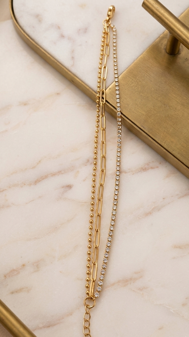 Coco Pearls Stainless Steel Anti Tarnish Gold chain and crystal bracelet on a gray stone surface