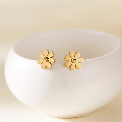 Coco pearls stainless Steel anti tarnish Gold flower-shaped earrings on a white dish with a beige background