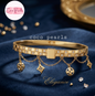 Coco pearls stainless Steel anti tarnish gold-tone Coco Pearls bangle bracelet with rhinestone-set segments and dangling chain charms, displayed on a dark blue satin fabric background with a gold mirror edge in the background.