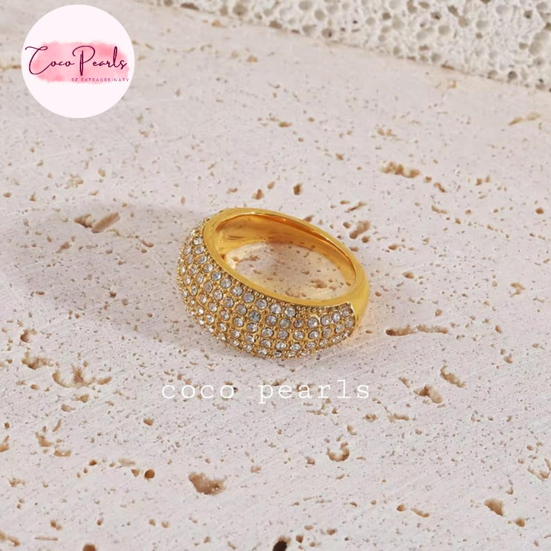 Coco pearls stainless Steel anti tarnish gold ring with a double row of small clear crystals, displayed on a textured beige stone surface.