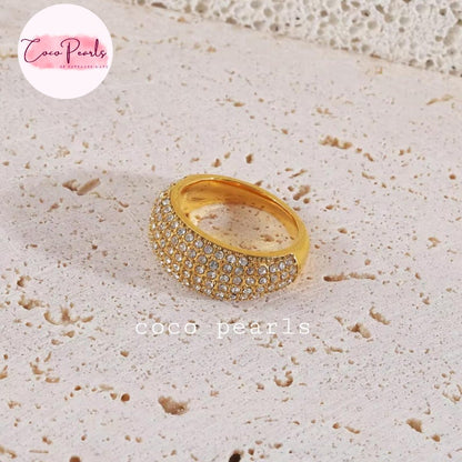 Coco pearls stainless Steel anti tarnish gold ring with a double row of small clear crystals, displayed on a textured beige stone surface.