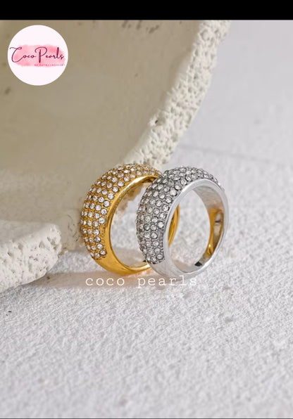 Coco pearls stainless Steel anti tarnish Two slim dome-shaped rings with rows of clear stones, one in yellow gold and one in silver, displayed on a textured white surface