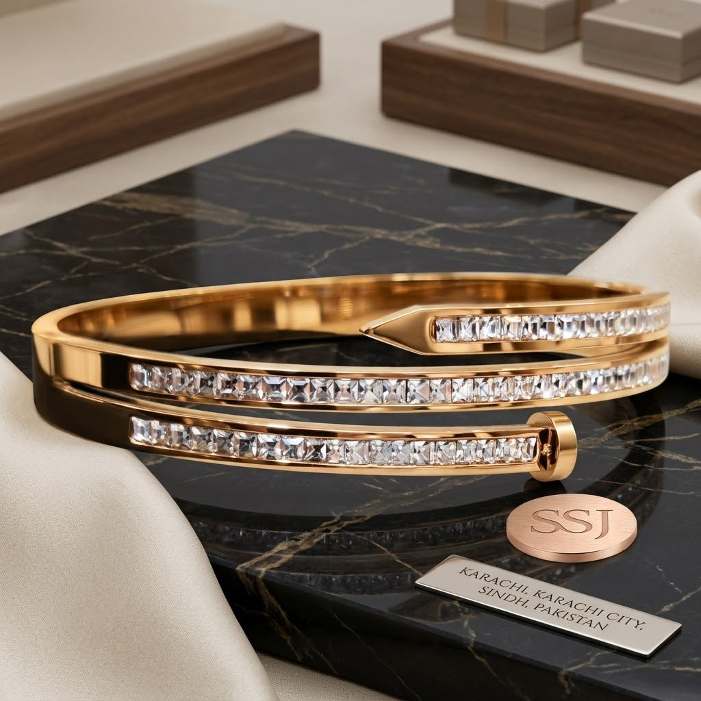 Coco pearls stainless Steel anti tarnish double-strand gold bangle bracelet with pavé-set clear crystals, displayed on a black marble slab with white satin fabric