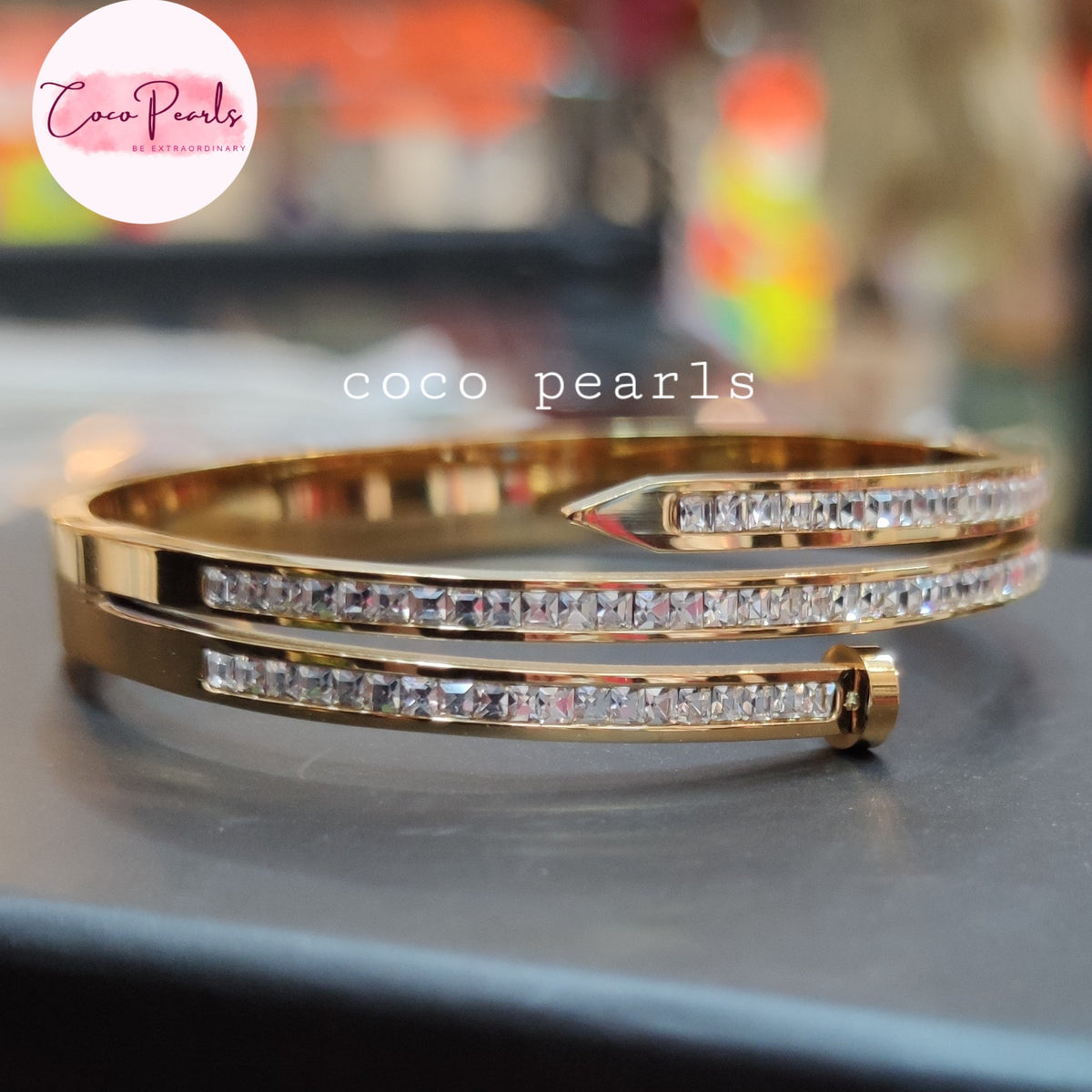Coco pearls stainless Steel anti tarnish gold-plated bangle bracelet with two rows of clear pavé-set cubic zirconia crystals, displayed on a dark surface