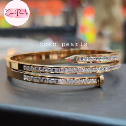 Coco pearls stainless Steel anti tarnish gold-plated bangle bracelet with two rows of clear pavé-set cubic zirconia crystals, displayed on a dark surface