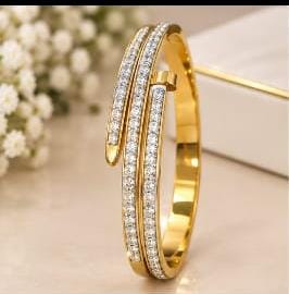 Coco pearls stainless Steel anti tarnish gold-plated hinged bangle bracelet with two parallel rows of clear pavé-set stones, displayed on a light beige surface